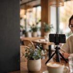 Short-form video strategy cover, creator filming video on a phone tripod in a cafe
